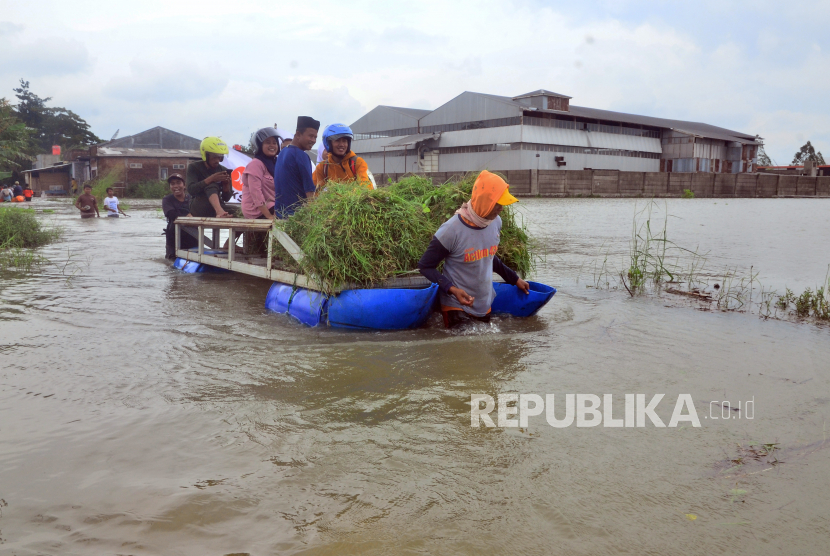 Relawan membantu warga melintasi jalan yang terendam banjir dengan perahu karet di Dusun Karangturi, Setrokalangan, Kaliwungu, Kudus, Jawa Tengah, Senin (2/1/2023). Menurut data BPBD setempat, banjir akibat intensitas hujan yang tinggi sejak Jumat (30/12/2022) itu semakin meluas dan menyebabkan 27.554 jiwa di 21 desa dari lima kecamatan terdampak dan 652 jiwa diantaranya mengungsi. 