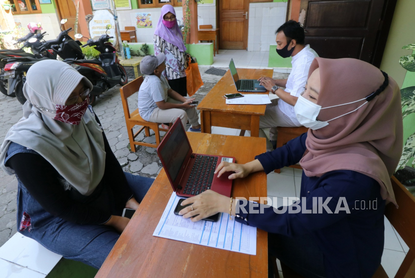 Dua orang guru membantu wali murid mengisi data saat Penerimaan Peserta Didik Baru (PPDB) daring jalur zonasi tingkat SMP di SD Negeri Pesantren 2, Kota Kediri, Jawa Timur,  beberapa waktu lalu.