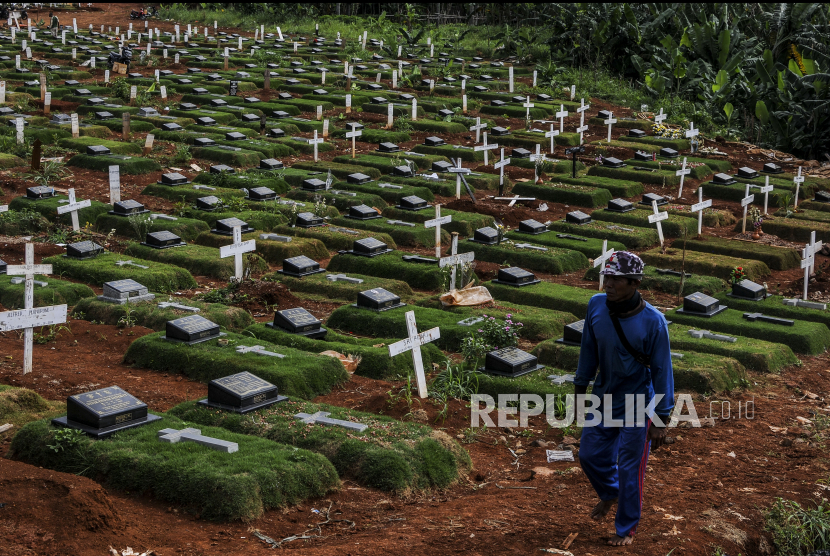 Petugas melintas di dekat makam Covid-19 di TPU Pondok Ranggon, Jakarta, Selasa (29/12). Blok makam Covid-19 di TPU Pondok Ranggon untuk jenazah muslim maupun non muslim sudah penuh dengan total 4.650 jenazah telah dimakamkan sepanjang Maret hingga 25 Desember 2020. Republika/Putra M. Akbar