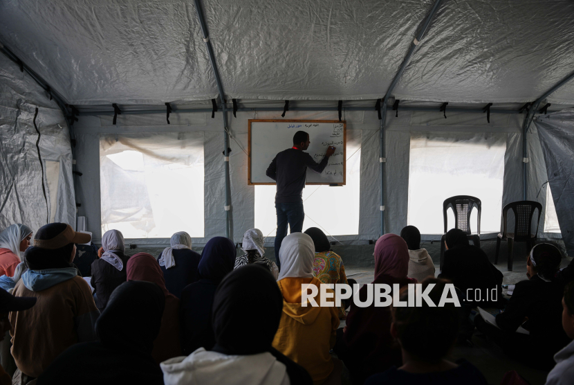 Siswa Palestina mengikuti pelajaran di dalam tenda darurat yang didirikan di Khan Younis, Jalur Gaza. Perang Israel di Gaza telah membuat anak-anak Palestina mengungsi, trauma, dan kehilangan kesempatan untuk mendapatkan pendidikan.
