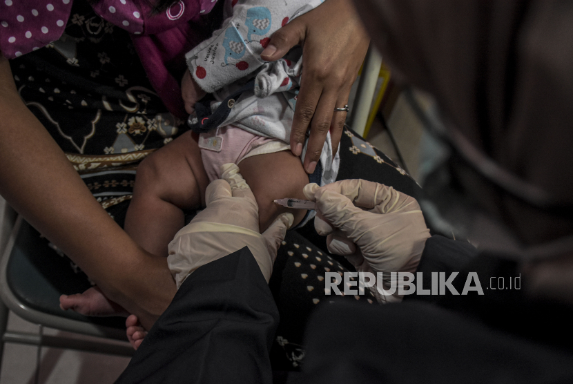 Petugas kesehatan menyuntikan vaksin polio kepada seorang anak.