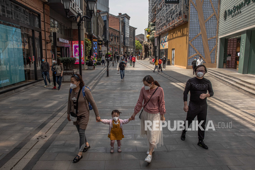 Sejumlah orang dengan memakai masker berjalan di area perbelanjaan, Wuhan, Cina, Senin (6/4). 