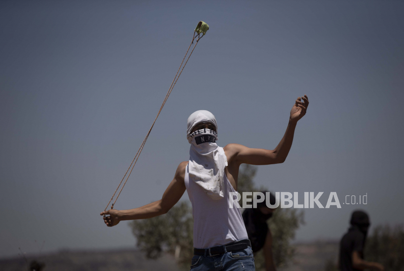  Seorang pengunjuk rasa Palestina menggunakan ketapel untuk melemparkan batu selama protes terhadap pos terdepan pemukiman Yahudi Tepi Barat Eviatar yang dengan cepat didirikan bulan lalu, di desa Palestina Beita, dekat kota Nablus, Tepi Barat, Jumat, 25 Juni 2021.