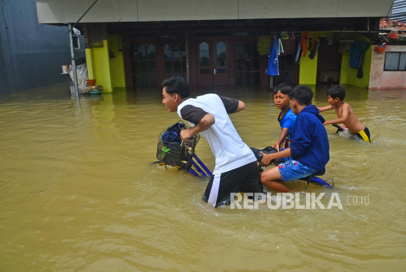 Sejumlah anak menuntun sepeda melewati jalan yang terendam banjir di Desa Temulus, Mejobo, Kudus, Jawa Tengah.