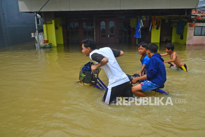 Sejumlah anak menuntun sepeda melewati jalan yang terendam banjir di Desa Temulus, Mejobo, Kudus, Jawa Tengah, Ahad (1/1/2023). Banjir akibat intensitas hujan yang tinggi sejak Jumat (30/12/2022) di wilayah tersebut menyebabkan belasan ribu rumah di 16 desa dari empat kecamatan terendam. 