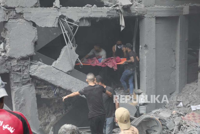 Warga Palestina mengevakuasi korban dari bangunan yang hancur akibat serangan udara Israel di Kota Gaza, pada 27 Oktober 2023.