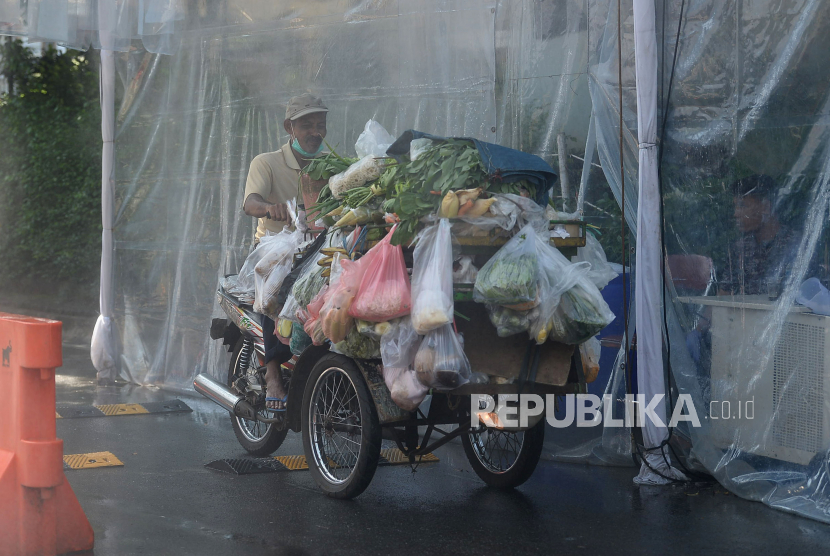 Pedagang sayur melewati tenda sterilisasi yang mengadung cairan disinfektan di kompleks Pondok Indah Gedung Hijau, Jakarta, Selasa (31/3). Setiap kendaraan warga dan tamu yang memasuki kawasan tersebut diwajibkan masuk ke dalam tenda sterilisasi