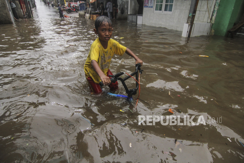 Seorang anak bermain air saat banjir di Kampung Utan Jaya, Citayam, Depok, Jawa Barat, Selasa (20/10/2020). Banjir tersebut disebabkan karena meluapnya aliran kali dan hujan deras yang mengguyur Kota Depok. 