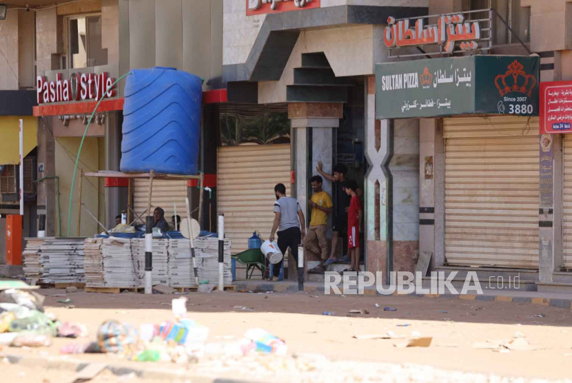 Orang Sudan berdiri di depan sebuah toko di Khartoum, Sudan, (19/4/2023). Perebutan kekuasaan meletus sejak 15 April antara tentara Sudan yang dipimpin oleh Panglima Angkatan Darat Jenderal Abdel Fattah al-Burhan dan paramiliter Pasukan Dukungan Cepat (RSF) dipimpin oleh Jenderal Mohamed Hamdan Dagalo, mengakibatkan sedikitnya 200 kematian menurut asosiasi dokter di Sudan.