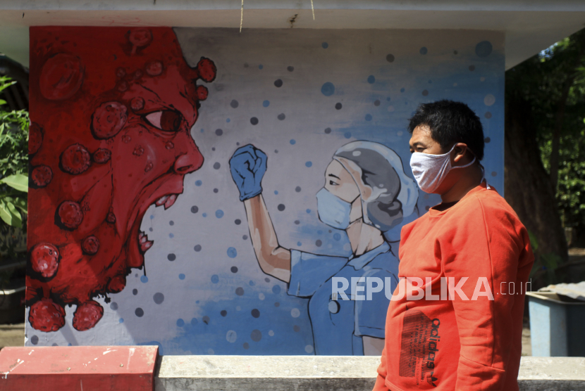 Warga melintas di dekat mural bergambar tenaga medis dan Virus Corona di kawasan Bantul, Yogyakarta. Sebagian besar dari penyebaran Covid-19 yang ada di Kota Yogyakarta terjadi di lingkungan keluarga.. 