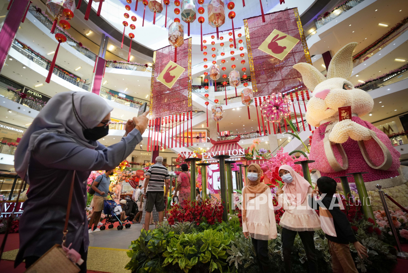 Seorang wanita memotret anak-anaknya di depan dekorasi tahun baru Imlek di dalam pusat perbelanjaan di Kuala Lumpur, Malaysia, Jumat (6 Januari 2023). Tahun Baru Imlek dimulai pada 22 Januari, menandai dimulainya Tahun Imlek Kelinci, menurut zodiak Cina.