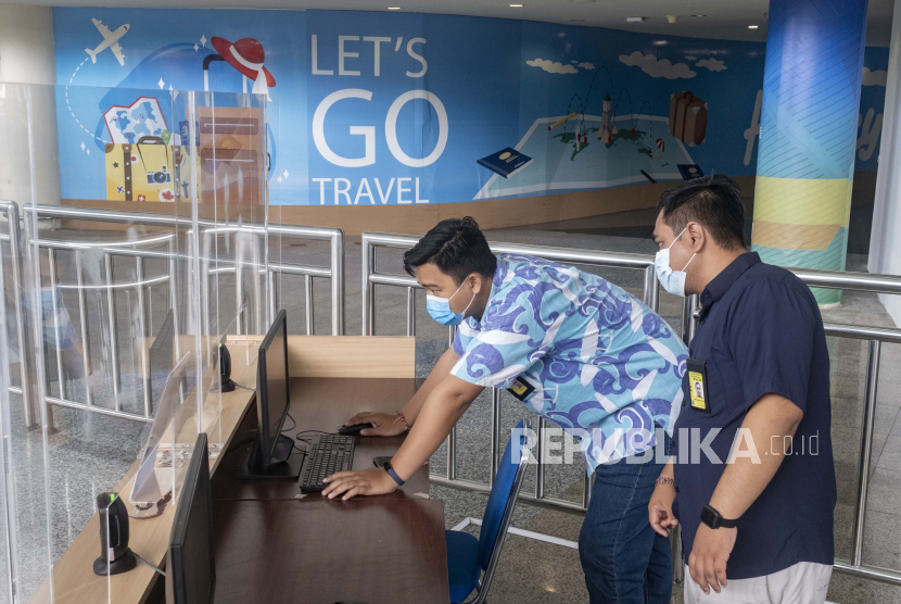  Pekerja bandara memeriksa komputer di area kedatangan internasional selama pembukaan bandara Internasional Ngurah Rai di Bali, Indonesia, 14 Oktober 2021. 