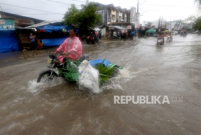 Warga melintas di jalan yang tergenang banjir di Desa Neusu, Banda Aceh, Aceh, Jumat (8/5/2020). Hujan deras yang terjadi sejak Kamis (7/5/2020) mengakibatkan ribuan rumah di sembilan kecamatan digenangi air dengan ketinggian hampir satu meter