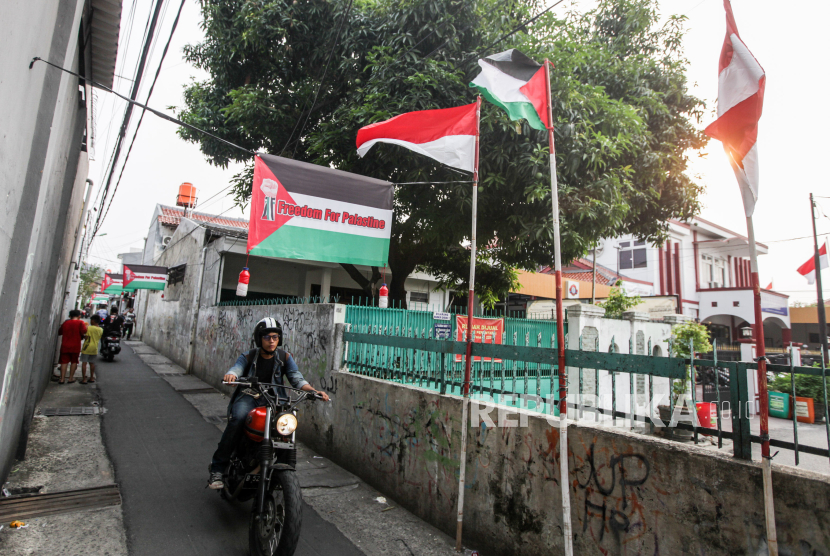 Pengendara motor melintas di dekat spanduk dukungan untuk Palestina di Jalan Palmerah 2E RT 10 RW 9, Jakarta Barat, Kamis (9/11/2023). Deretan spanduk bermotif bendera Palestina yang terpasang di gang pemukiman warga tersebut untuk menunjukan solidaritas bela Palestina yang saat ini masih terlibat konflik perang dengan Israel.