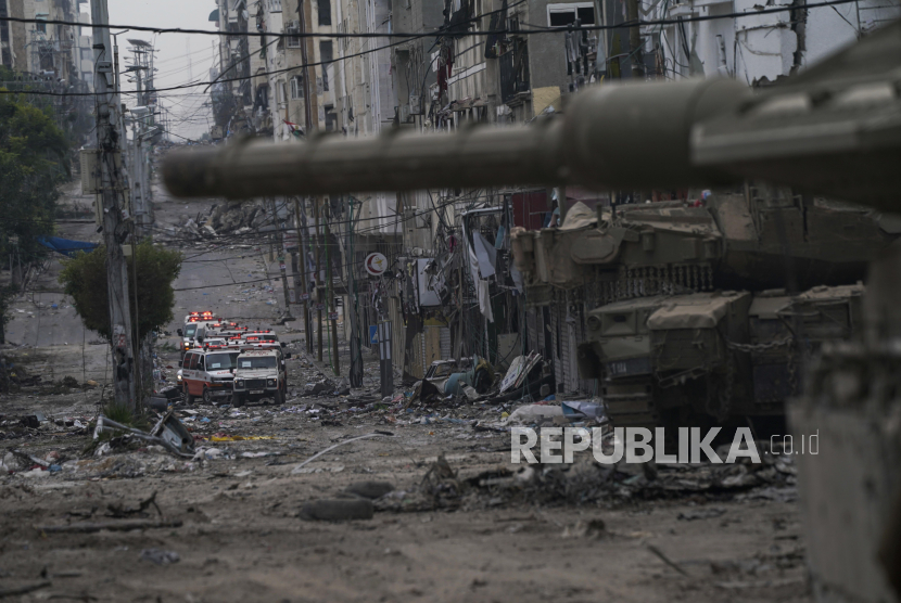 Ambulans terlihat di jalan dekat tank pasukan Israel selama operasi darat tentara Israel di Jalur Gaza, Rabu, 22 November 2023.