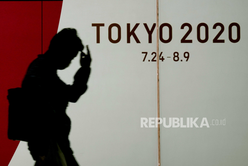 Pejalan kaki yang mengenakan topeng pelindung sedang berjalan melewati poster acara Olimpiade Tokyo 2020, yang dijadwalkan kembali dibuka pada 23 Juli 2021 karena pandemi virus coronavirus COVID-19, di Tokyo, Jepang, 15 Juli 2020. 
