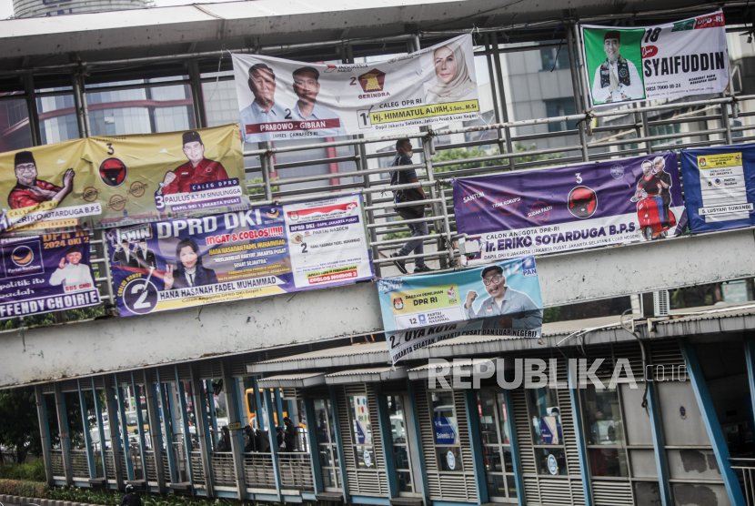 Warga berjalan melewati jembatan penyeberangan orang yang dipasangi spanduk peserta Pemilu 2024 di kawasan Salemba, Jakarta, Jumat (8/12/2023). Memasuki musim kampanye spanduk para peserta pemilu 2024 mulai banyak bertebaran di jalanan meskipun kehadirannya dinilai mengganggu pemandangan dan merusak estetika kota.