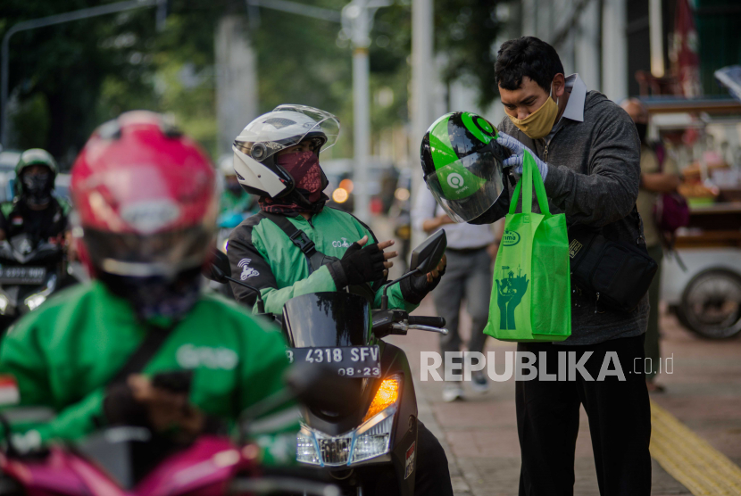 Pengemudi ojek daring menurunkan penumpang di kawasan stasiun Palmerah pada hari pertama diperbolehkannya ojek daring mengangkut penumpang, Jakarta, Senin (8/6). Survei menunjukkan transportasi daring jauh lebih diandalkan masyarakat daripada angkutan feeder konvensional.