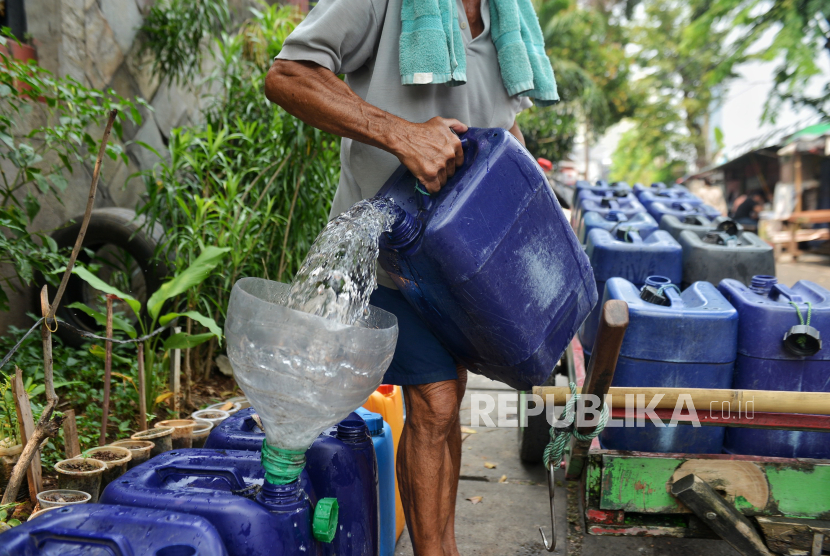 Tarmud (65 tahun) mengantarkan air bersih kepada pelanggan di kawasan Pademangan, Jakarta Utara, Senin (6/5/2024).