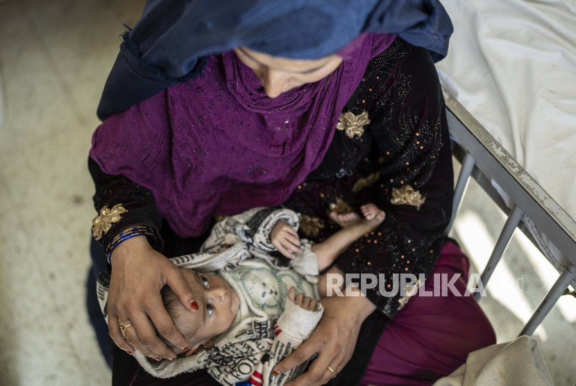 Saliha menggendong bayinya Najeeb yang berusia empat bulan saat ia menjalani perawatan di bangsal malnutrisi Rumah Sakit Anak Indira Gandhi di Kabul, Afghanistan, Rabu, 8 Desember 2021. 