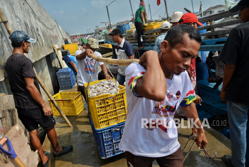 Pekerja mengangkat ikan hasil tangkapan nelayan.