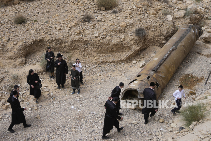 Warga Yahudi memeriksa puing-puing yang diyakini sebagai rudal Iran yang dicegat di dekat kota Arad, Israel selatan, Ahad, (28/4/2024).
