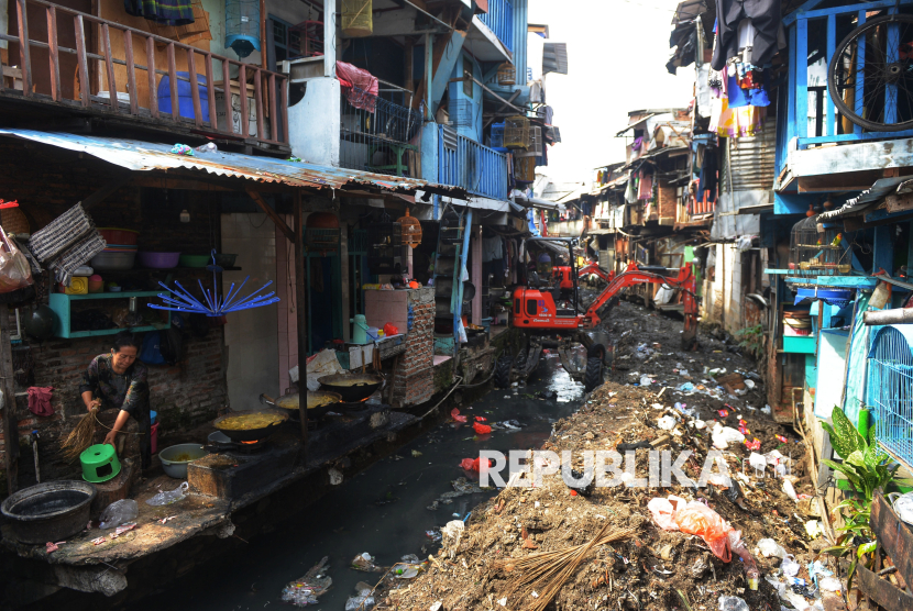 Warga beraktivitas di dekat alat berat yang digunakan untuk membersihkan sedimen aliran Kali Krukut di kawasan Kebon Melati, Jakarta, Rabu (5/11/2025). Pembersihan sampah serta pengerukan sedimen tanah dan lumpur dilakukan untuk mengatasi pendangkalan yang selama ini menjadi penyebab banjir di kawasan padat penduduk. Pendangkalan membuat aliran air tersendat, terutama saat curah hujan tinggi. Pemerintah Provinsi DKI Jakarta mengimbau masyarakat untuk turut menjaga kebersihan lingkungan dengan tidak membuang sampah ke saluran air. Kolaborasi antara pemerintah dan warga dinilai penting untuk mewujudkan Jakarta yang bebas banjir dan lebih nyaman ditinggali.