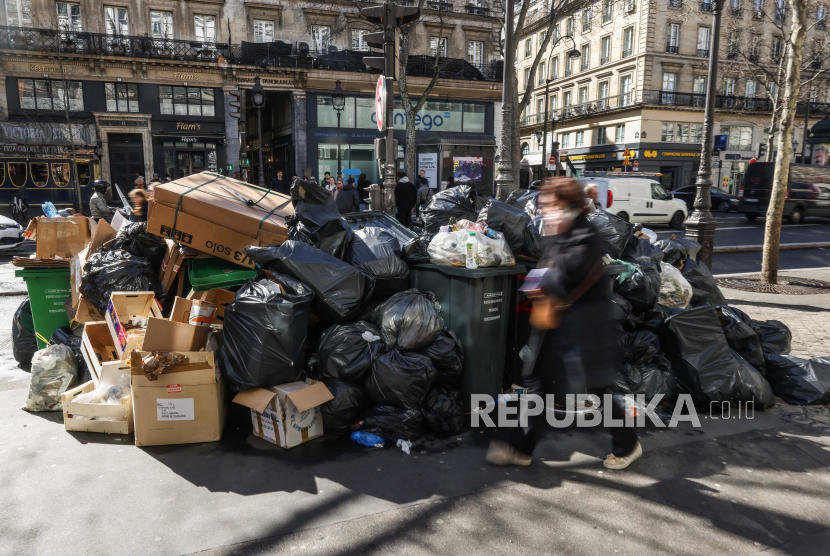  Orang-orang lewat di samping tong sampah yang penuh dengan sampah di Paris, Prancis. Tumpukan sampah ini menjadi tempat bermain atau playground bagi para tikus.