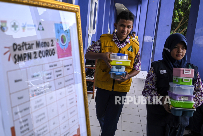 Dua siswa membawa tempat berisi makan saat simulasi program makan siang gratis di SMP Negeri 2 Curug, Kabupaten Tangerang, Banten, Kamis (29/2/2024).