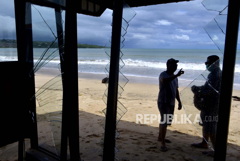 Warga mengamati bangunan kafe yang rusak akibat diterjang gelombang air laut di kawasan Pantai Jimbaran, Badung, Bali, Kamis (28/5/2020). Gelombang tinggi dan pasang air laut yang terjadi di kawasan perairan tersebut sejak Rabu (27/5), merusak sejumlah bangunan kafe serta mengakibatkan nelayan setempat tidak dapat melaut