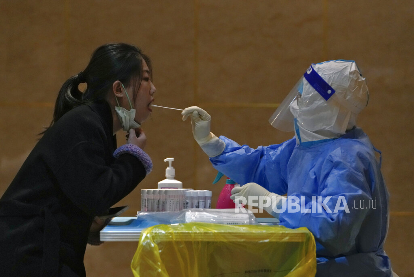 Seorang pekerja medis dengan alat pelindung melakukan tes COVID-19.