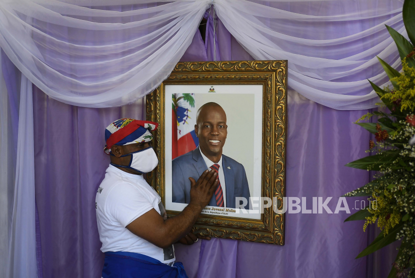  Seorang pria menyentuh potret mendiang Presiden Haiti Jovenel Moïse di luar Katedral tempat upacara peringatan untuknya berlangsung di Cap-Haitien, Haiti, Kamis, 22 Juli 2021. Moïse dibunuh di rumahnya pada 7 Juli.