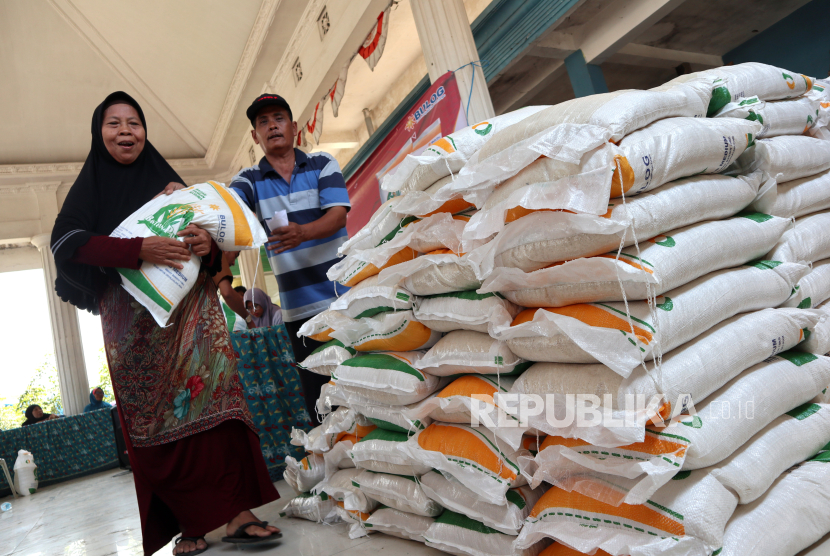 Warga penerima bantuan membawa sekarung beras saat penyaluran  bantuan pangan cadangan beras (ilustrasi)