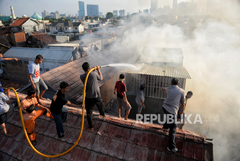 Warga membantu Dinas Penanggulangan Kebakaran dan Penyelamatan (Gulkarmat) memadamkan api yang membakar pemukiman di Jalan Anyer 15 RT 6 RW 9, Menteng, Jakarta Pusat, Jumat (29/9/2023). 