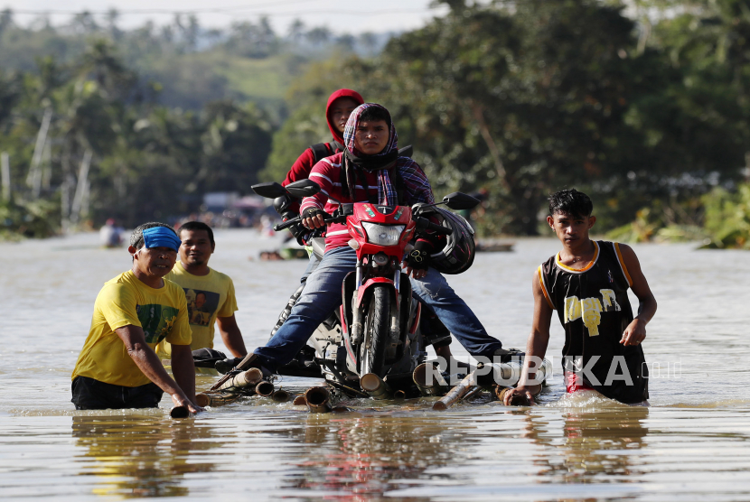 Filipina Bergegas Selamatkan Ribuan Orang dari Badai Vamco. Pengendara sepeda motor yang terdampar mengendarai perahu di jalan yang banjir setelah Topan Vamco di kota Lopez, provinsi Quezon, Filipina, 13 November 2020. 