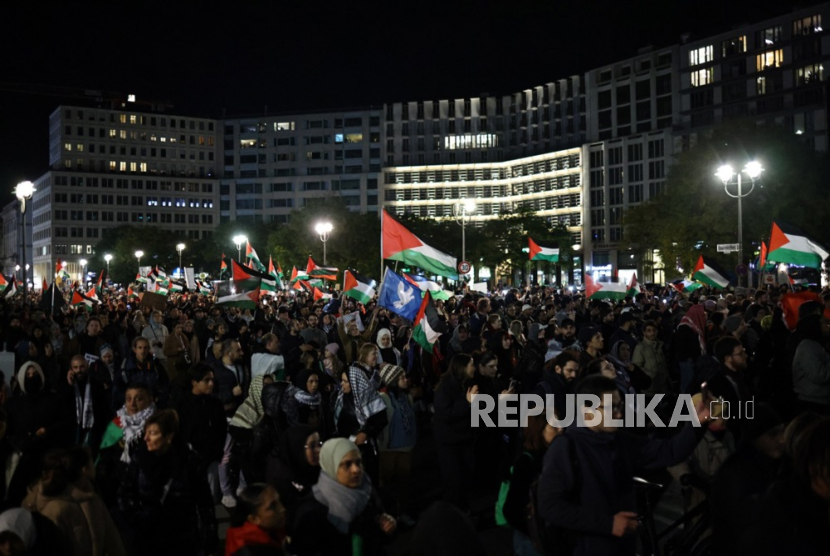 Para pengunjuk rasa berjalan dengan bendera saat aksi solidaritas Palestina, di Berlin, Jerman, Ahad (5/11/2023).
