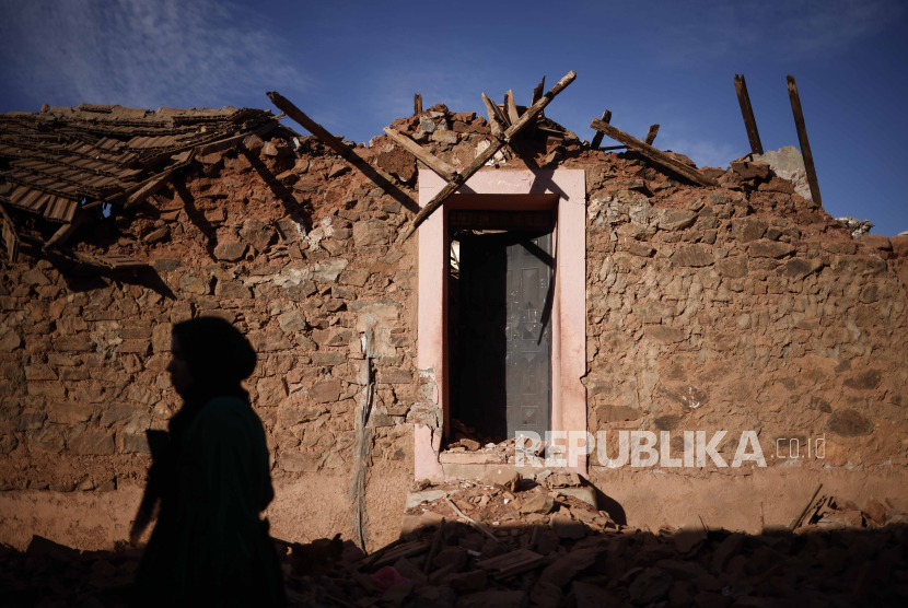 Seorang wanita melewati bangunan yang rusak akibat gempa bumi susulan di Ouirgane, selatan Marrakesh, Maroko, (10/9/2023).