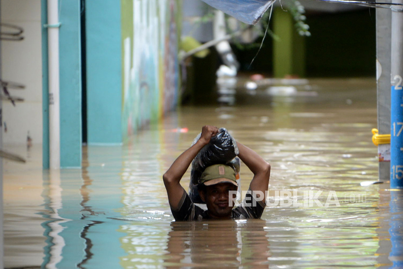 Seorang warga melintasi banjir yang merendam kawasan Kebon Pala, Kampung Melayu, Jatinegara, Jakarta Timur, Senin (27/2/2023). BPBD DKI Jakarta sebut banjir di tujuh kelurahan sebabkan 189 jiwa masih mengungsi.