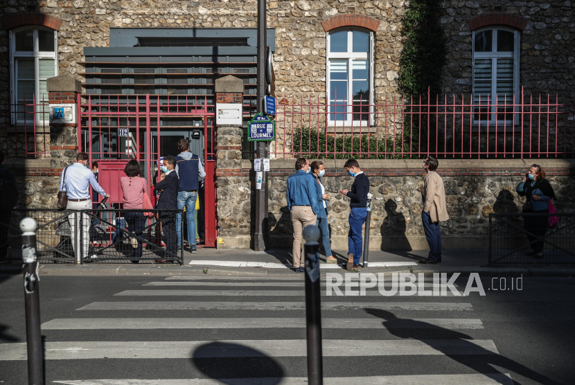 Orang tua menunggu di luar sekolah di Prancis.