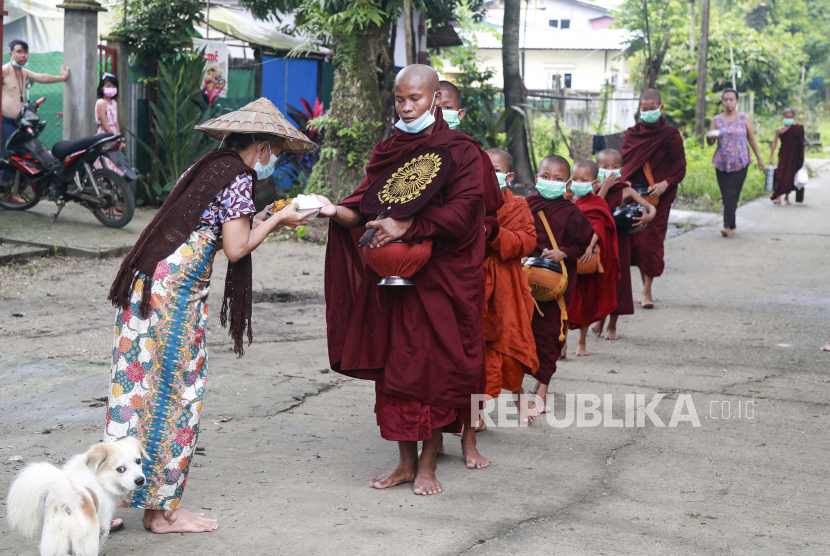 Biksu Buddha yang mengenakan masker menerima makanan dari umat saat mereka mengumpulkan sedekah pagi Kamis, 15 Juli 2021, di Yangon, Myanmar.