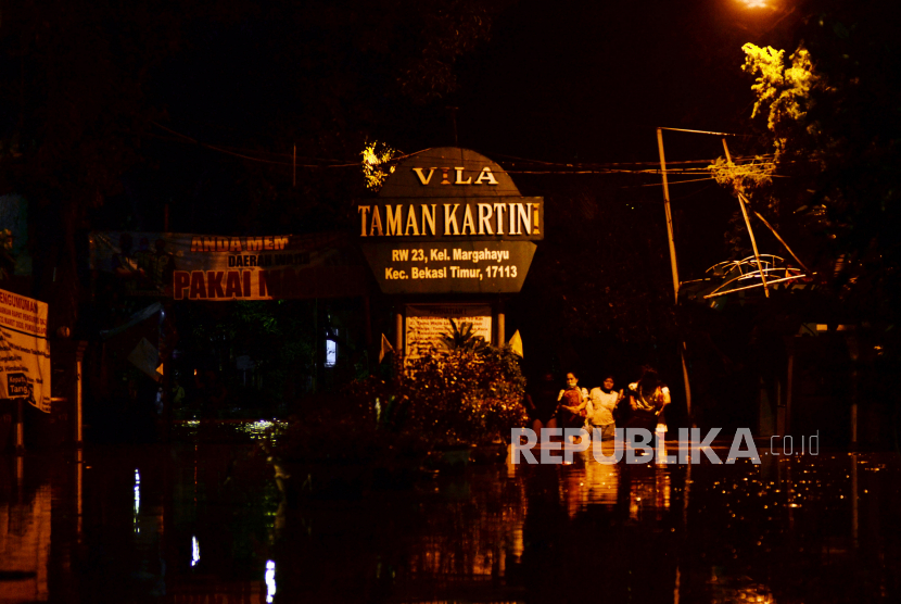 Sejumlah warga melintasi banjir di Perumahan Taman Vila Kartini, di Bekasi.