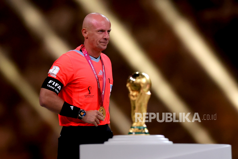 Wasit Polandia Szymon Marciniak berjalan melewati trofi Piala Dunia setelah memimpin Final Piala Dunia FIFA 2022 antara Argentina dan Prancis di stadion Lusail, Lusail, Qatar, 18 Desember 2022.