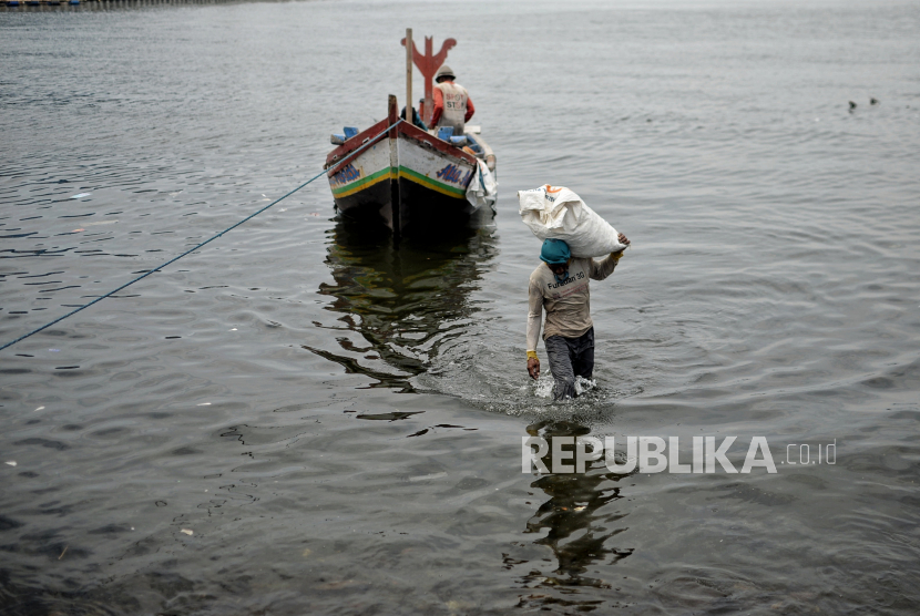 Nelayan membawa karung hasil tangkapan berisi kerang ijo sebelum diolah di kawasan Cilincing, Jakarta Utara, Senin (21/2/2022).