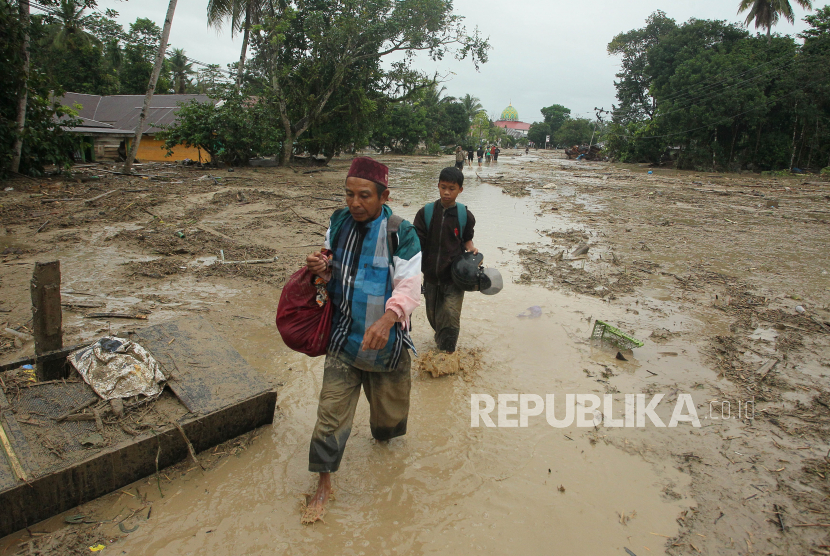 Dua warga melintasi lumpur akibat banjir bandang di Desa Radda, Kabupaten Luwu Utara, Sulawesi Selatan, Selasa (14/7/2020). Petugas BPBD Sulawesi Selatan masih menginventarisasi kerugian akibat banjir bandang pada Senin, 13 Juli 2020 yang mengakibatkan puluhan rumah terbawa arus, dua orang meninggal dan tujuh orang hilang. 