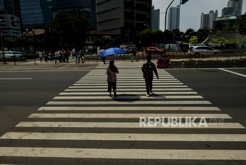 Perkeja melindungi tubuh dari terik matahari menggunakan payung saat berjalan di kawasan Sudirman, Jakarta, Senin (18/12/2023). BMKG mengungkapkan fenomena suhu panas meningkat terjadi beberapa hari ini disebabkan oleh aktivitas dinamika atmosfer yang berdampak pada naik turunnya suhu permukaan laut sehingga potensi curah hujan rendah untuk wilayah Indonesia. Deputi Bidang Meteorologi, Klimatologi dan Geofisika (BMKG) Guswanto mengatakan potensi curah hujan rendah tersebut diketahui dari analisis kondisi iklim global.