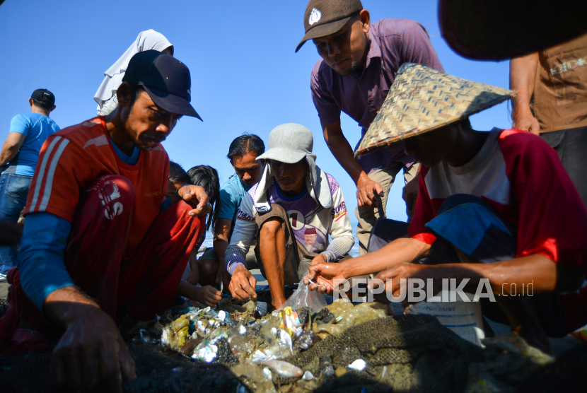 Nelayan memindahkan ikan hasil tangkapannya yang bercanpur dengan sampah, di Pantai Purus, Padang, Sumatera Barat, Sabtu (18/2/2023). Nelayan pukat tepi mengeluhkan hasil tangkapannya yang hampir sama banyak dengan sampah plastik yang terjaring.  