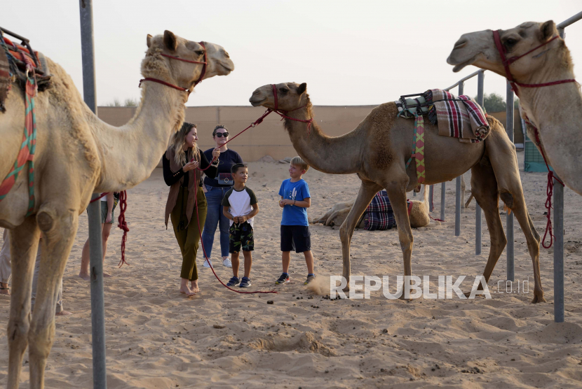 UEA Umumkan UU Baru yang Mengatur Keluarga untuk Ekspatriat Non-Muslim. Foto ilustrasi: Pendiri dan Pelatih Arabian Desert Camel Riding Center Linda Krockenberger, kiri pertama, berbicara dengan beberapa ekspatriat yang mengunjungi pusat tersebut selama Hari Unta Sedunia, di pinggiran Marmoom Dubai, Uni Emirat Arab, Rabu, 22 Juni 2022.