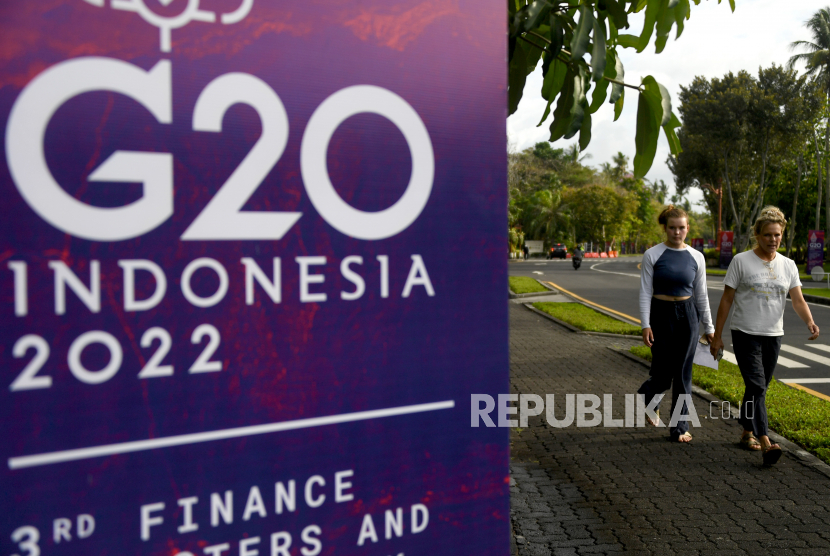 Turis asing berjalan melewati spanduk di dekat tempat utama pertemuan menteri keuangan dan gubernur bank sentral G-20 di Nusa Dua, Bali, Indonesia, beberapa waktu lalu.