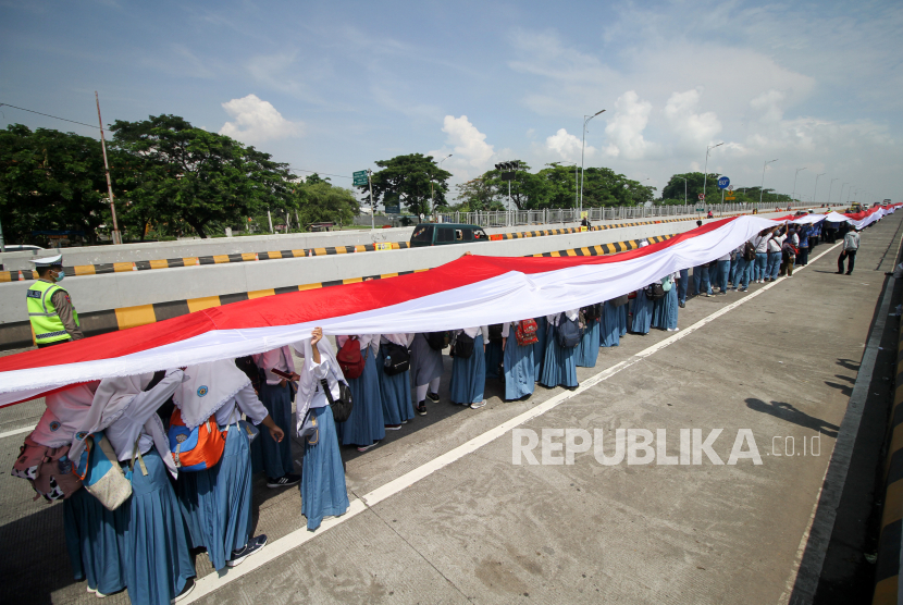 Puluhan siswa membentangkan bendera Merah Putih sepanjang 3.219 meter saat pemecahan rekor MURI di Jembatan Suramadu sisi Madura menuju Surabaya, Jawa Timur, Kamis (10/11/2022). Pemecahan rekor MURI pembentangan Bendera Merah Putih sepanjang 3.219 meter tersebut dalam rangka memperingati Hari Pahlawan 2022. 