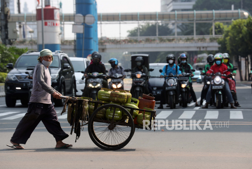  Seorang pedagang kaki lima membawa gerobak berisi tabung LPG (liquified Petroleum gas) saat melintasi jalan selama pembatasan COVID-19 di Jakarta, Selasa (3/8/2021).  Pemerintah dikabarkan bakal membatasi penjualan gas elpiji 3 kg di tingkat pengecer. 